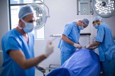 Group of surgeons performing operation in operation room at hospitalの写真素材