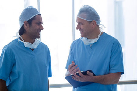 Surgeons discussing over medical reports in hospital corridorの写真素材
