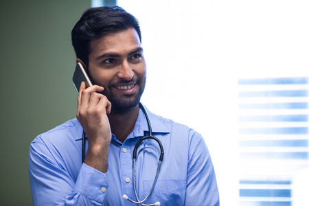 Doctor talking on mobile phone at the hospitalの写真素材