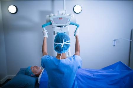 Nurse adjusting x-ray machine over patient in hospitalの写真素材