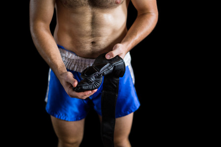 Mid section of boxer wearing grappling gloves against black background