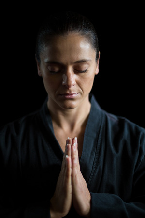 Female karate player in prayer pose against black backgroundの写真素材