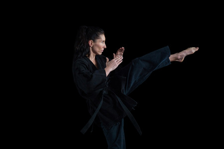 Female karate player performing karate stance against black backgroundの写真素材
