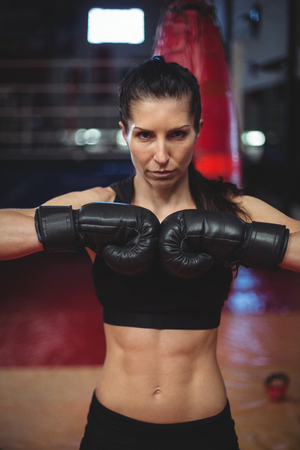 Female boxer performing boxing stance in fitness studioの写真素材