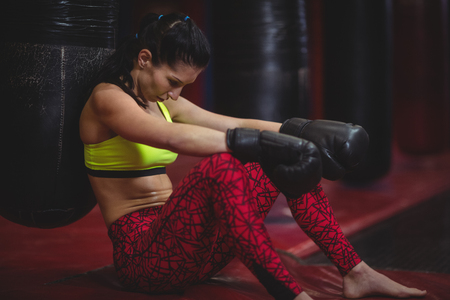 Tired female boxer leaning on punching bag in fitness studioの写真素材