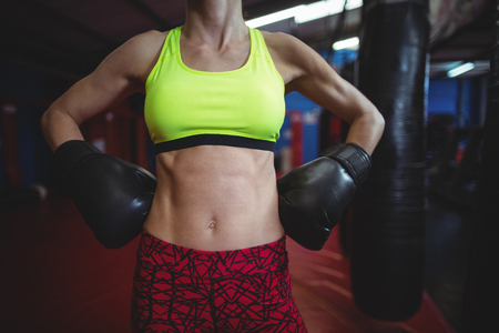 Mid section of female boxer standing with hands on hip in fitness studioの写真素材