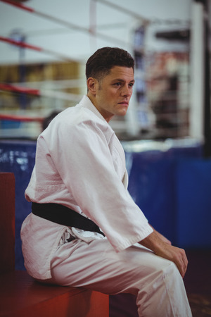 Thoughtful karate player sitting in fitness studioの写真素材