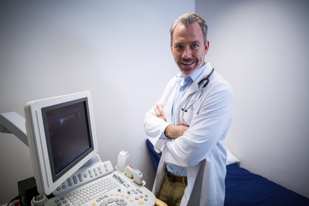 Portrait of doctor standing near patient monitoring machine in ward of hospital