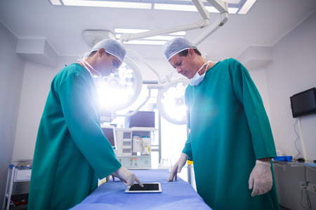 Surgeons using digital tablet in operation theater of hospital