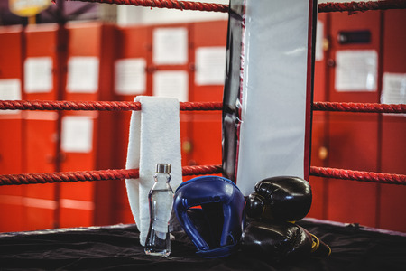 Boxing gloves, headgear, water bottle and a towel in a corner of boxing ring