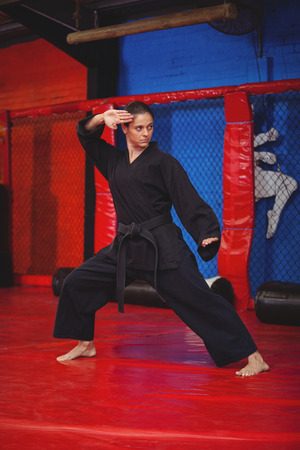Female karate player performing karate stance in fitness studioの写真素材