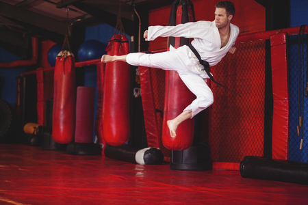Karate player performing kickboxing in fitness studioの写真素材