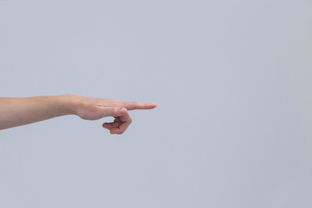 Hand of a woman pointing sideways against grey backgroundの写真素材