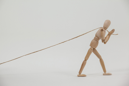 Wooden figurine pulling a rope against white background