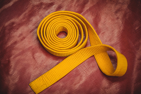 Rolled -up karate yellow belt on red backgroundの写真素材