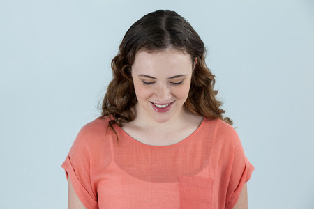 Close-up of smiling Woman looking down against grey background