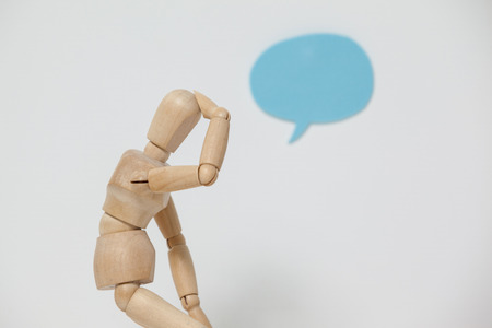 Tensed wooden figurine with hand on head against white backgroundの写真素材