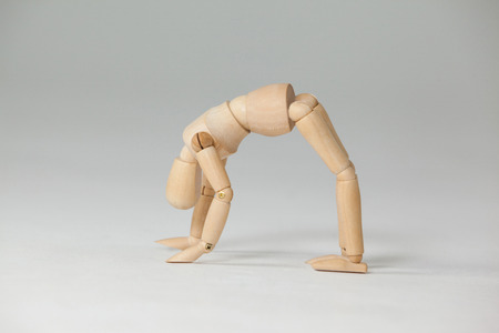 Wooden figurine exercising on floor against white backgroundの写真素材