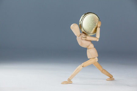 Wooden figurine holding a gold coin against white backgroundの写真素材