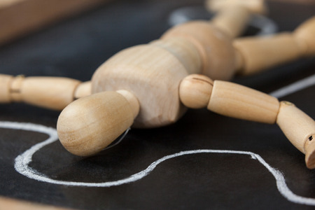 Wooden figurine lying on a slate board with border around his bodyの写真素材