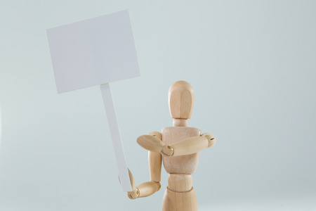 Wooden figurine holding blank sign board against white backgroundの写真素材