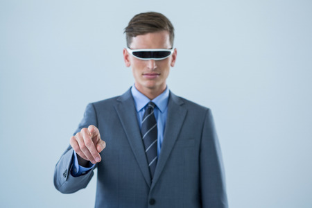 Businessman pointing his finger while using virtual reality glasses against white backgroundの写真素材