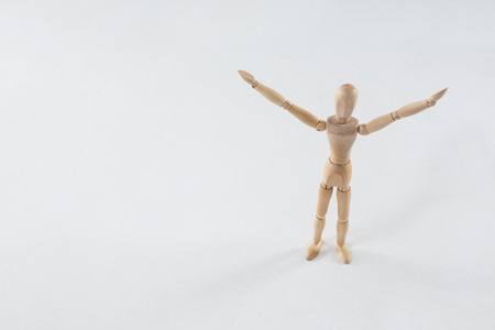 Wooden figurine standing on wooden floor with arms spreadの写真素材
