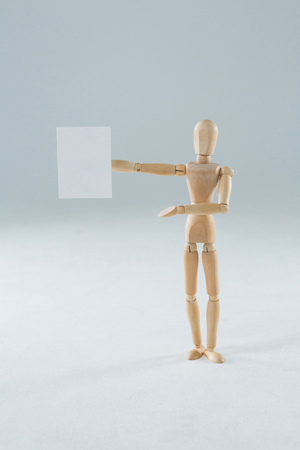 Wooden figurine holding blank placard against white backgroundの写真素材