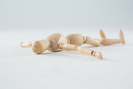 Wooden figurine lying on floor against white backgroundの写真素材