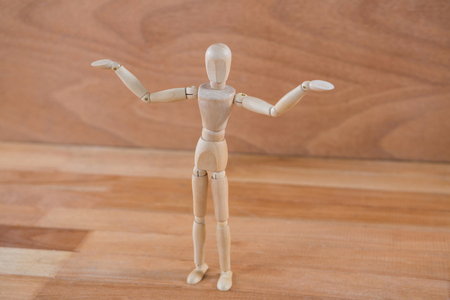 Wooden figurine standing on wooden floor with arms spreadの写真素材