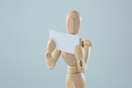 Wooden figurine holding blank placard against white backgroundの写真素材