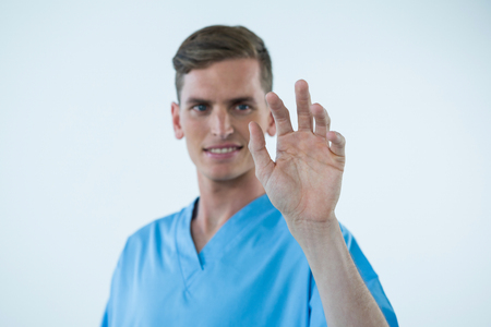 Smiling male nurse touching an invisible screen against white backgroundの写真素材