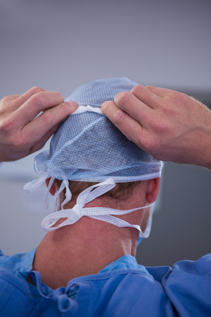 Surgeon tying surgical mask in operation room at hospitalの写真素材