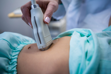 Mid section of female doctor doing ultrasound for patient at hospitalの写真素材