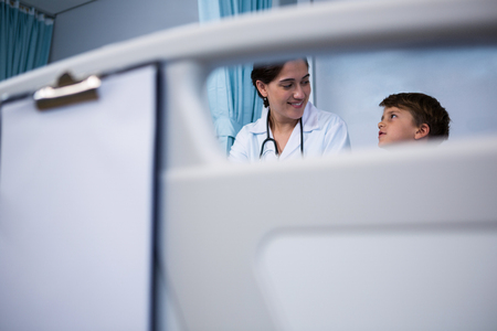 Smiling doctor interacting with patient in ward at hospitalの写真素材