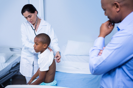 Doctor examining patient with stethoscope in ward at hospitalの写真素材