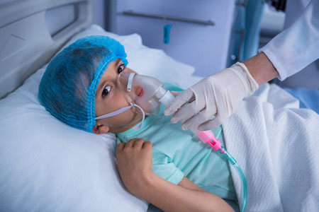 Doctor placing an oxygen mask on patient in ward at hospitalの写真素材