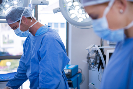 Female and male surgeon wearing surgical mask in operation theater at hospitalの写真素材