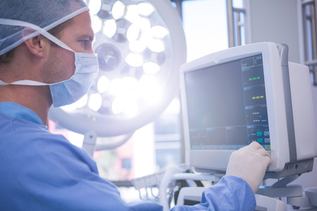 Male surgeon using patient monitoring machine in operation theater at hospitalの写真素材