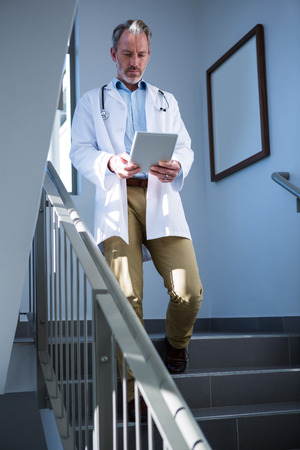 Doctor using digital tablet on staircase at hospitalの写真素材