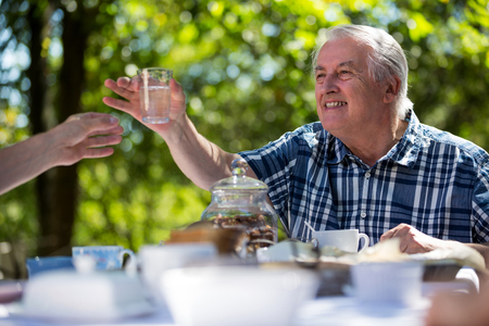 Senior men having breakfast in garden on a sunny dayの写真素材