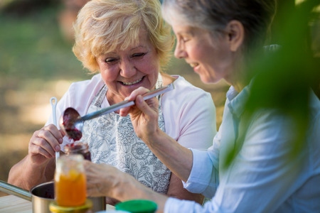 Senior women filling jam in a bottle at gardenの写真素材