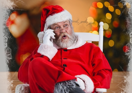 Santa talking on his phone while sitting on a chair against christmas backgroundの写真素材