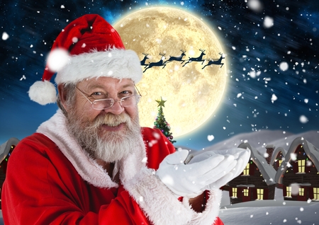 Portrait of santa pretending to hold digital generated christmas gifts at nightの写真素材