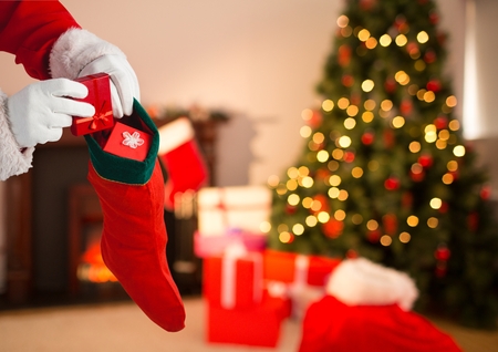 Close-up of Santa Claus putting gift boxes in Christmas stockingの写真素材
