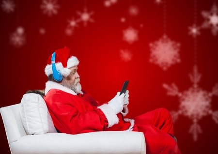 Santa claus sitting on chair listening music and using mobile phoneの写真素材