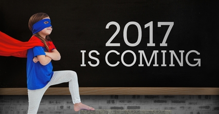 Girl in superhero costume standing near a black board with 2017 new year quotes