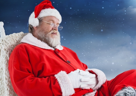 Santa claus sitting on chair and sleeping against skyの写真素材