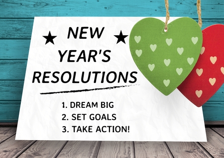 List of new year resolution goals written on card against wooden background