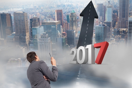 2017 against a composite image of business man looking at road leading towards sky in cityの写真素材